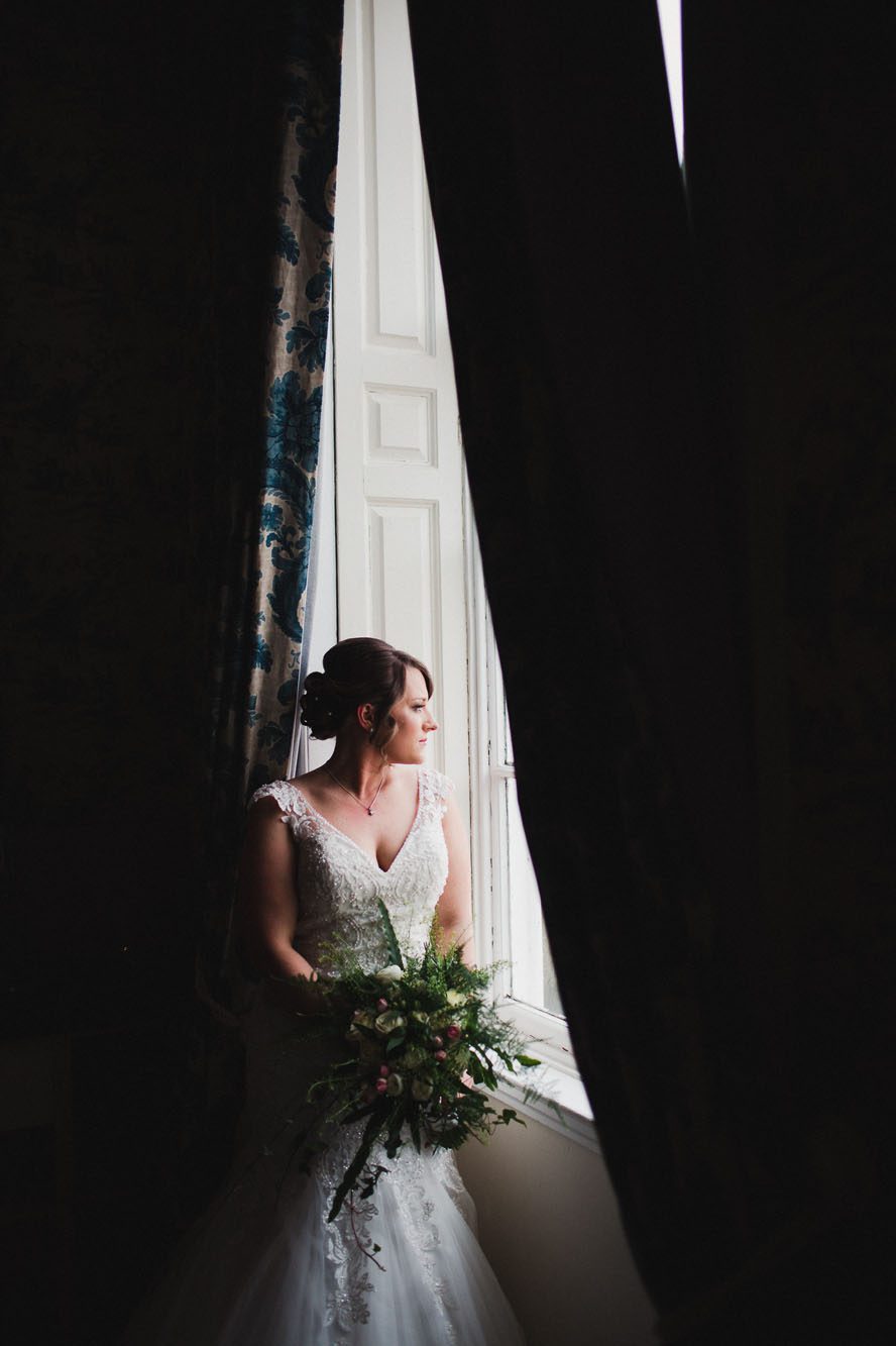 window light - bride standing in tall window, holding bouquet, bathed in light