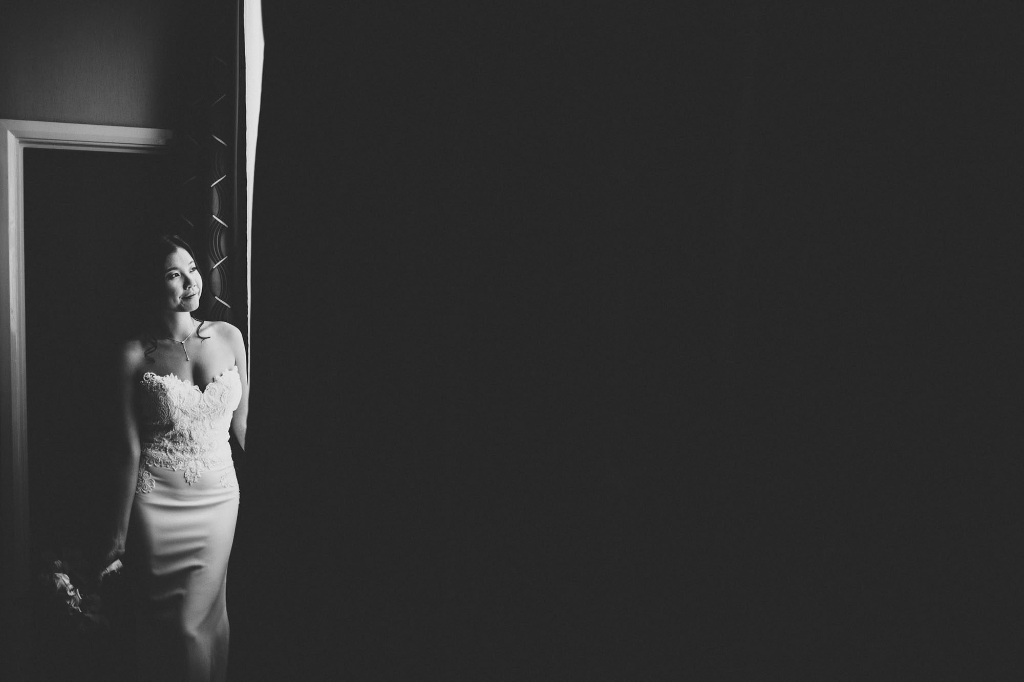 black and white portrait of bride standing in window light to the edge of frame