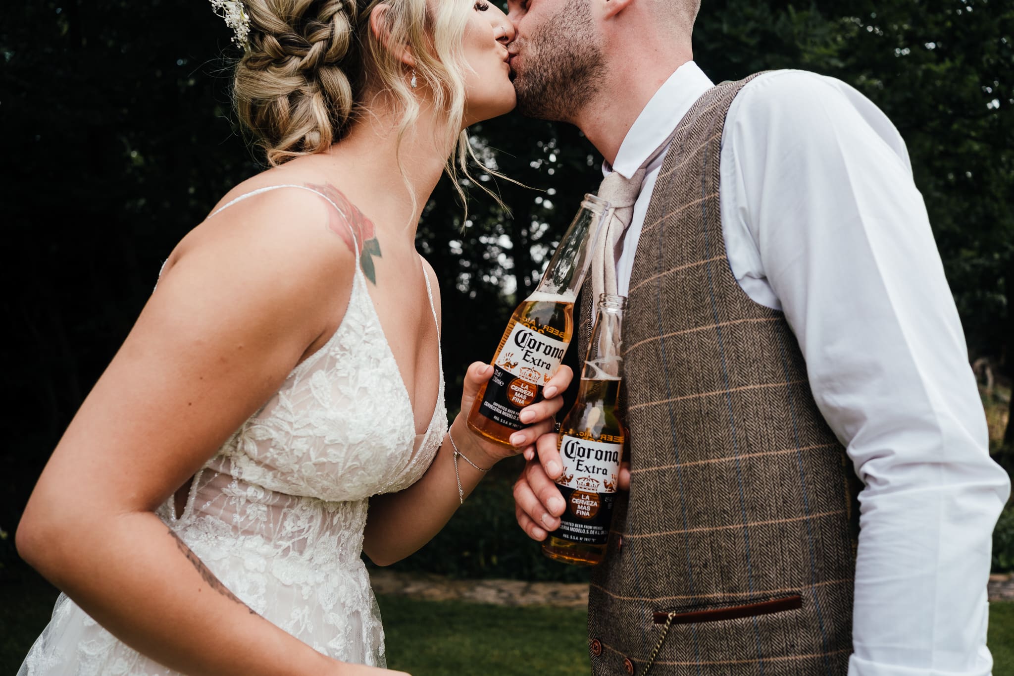 Bride and groom kissing holding corona beers