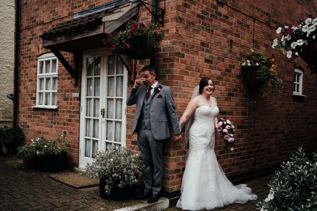 Wedding Photography at the Country Cottage hotel in Ruddington - First Meet pre ceremony photograph. Bride and groom holding hands. Groom wiping back tears.