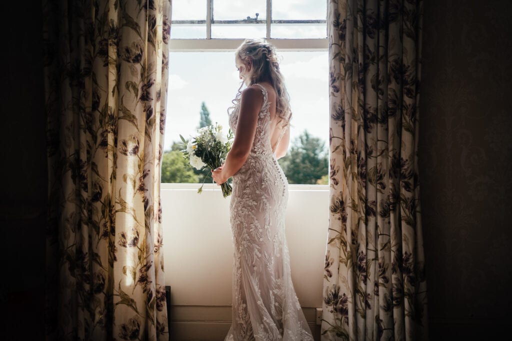 Bridal portrait of Beth standing in front of window at the Walled Garden at Beeston Fields 