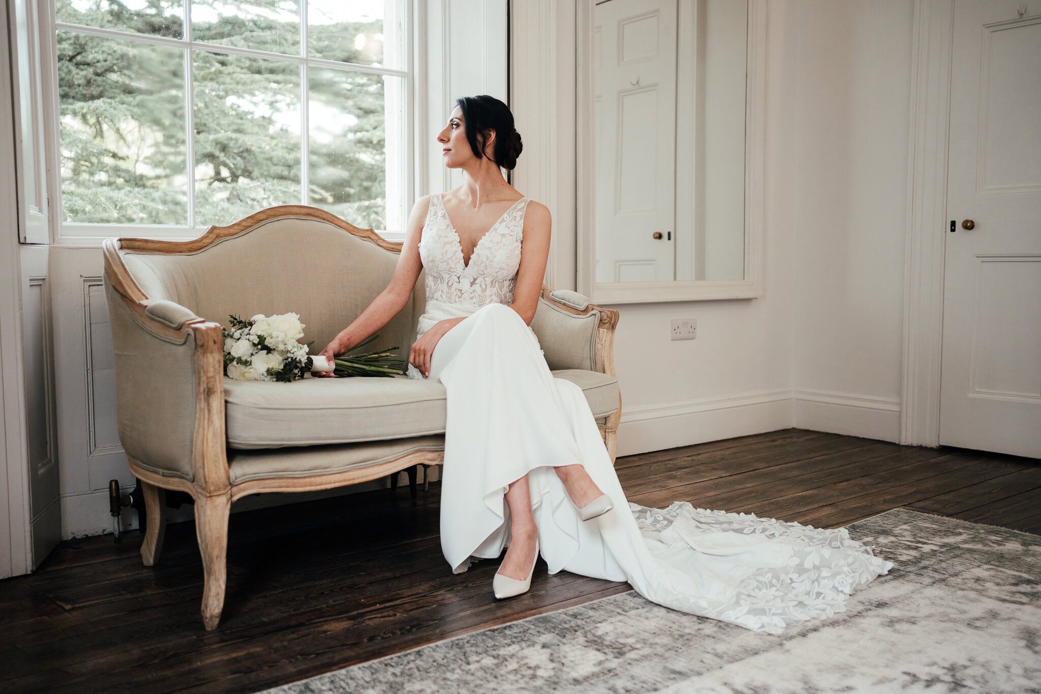 Aswarby Rectory wedding photography - bride sitting next to the window, elegant dress, bouquet by her side, gazing out of the window