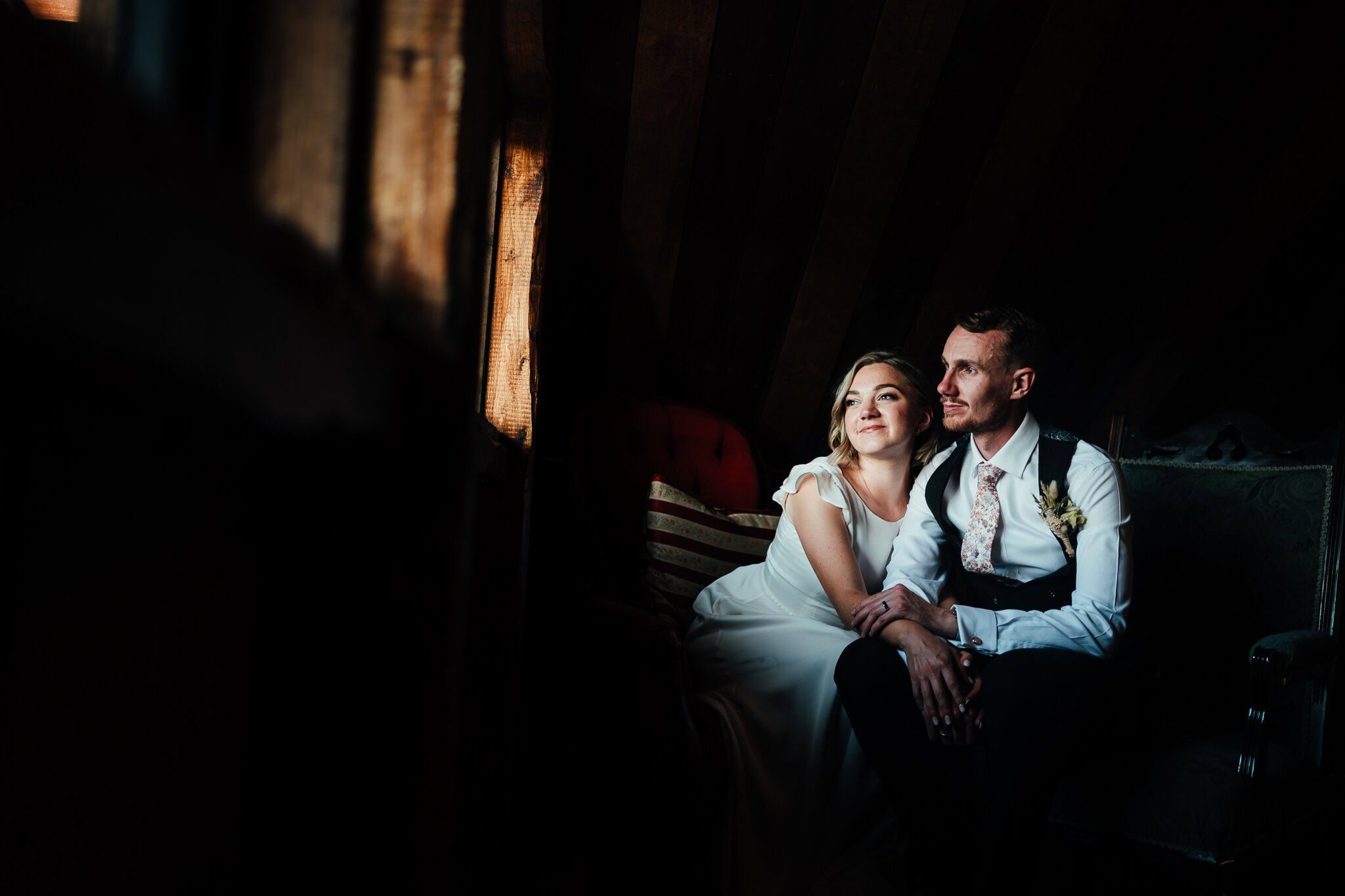 Willow Marsh Farm wedding - bride and groom sit in barn, lit by small window